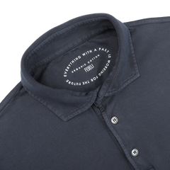 A navy blue polo shirt by Fedeli, made from organic cotton, features a white inner label reading "Everything with a past is working for the future. Crafted from organic Giza cotton. Feel it.