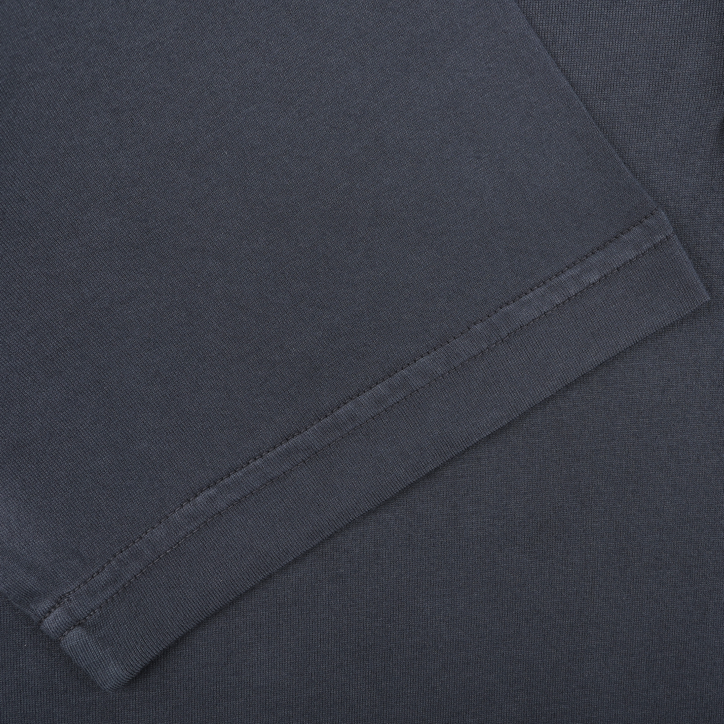 Close-up of the corner of a folded Navy Blue Organic Cotton Polo Shirt by Fedeli, showcasing its hem and texture.