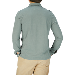 The back view of a man wearing a Fedeli Olive Green Organic Cotton LS Polo Shirt and khaki pants.