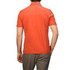 Seen from behind, a person wears an Orange Organic Cotton Capri Collar Polo Shirt by Fedeli and brown pants, epitomizing luxury casualwear.