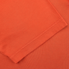 The Fedeli Orange Organic Cotton Capri Collar Polo Shirt showcases luxury casual wear with its close-up view of the sleeve, crafted from Giza cotton and featuring visible stitching along the edges.