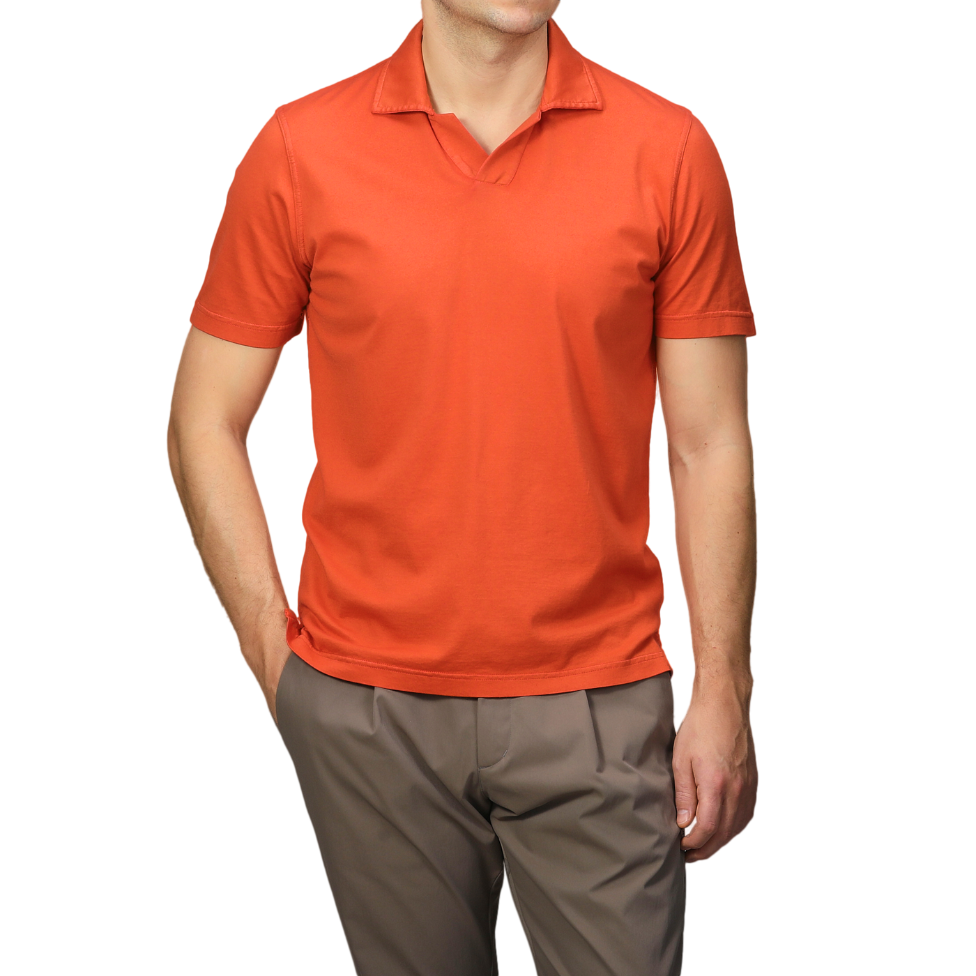 Elegantly attired in a Fedeli Orange Organic Cotton Capri Collar Polo Shirt and brown pants, a person stands out against a neutral backdrop.