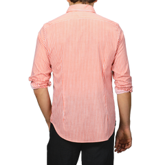 Person wearing an orange and white striped long-sleeve beach shirt from Fedeli, made from cotton stretch fabric, viewed from the back.