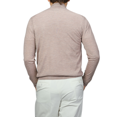 A person is seen from the back, wearing a Fedeli Taupe Beige Cashmere Silk 1/4 Zip Sweater and white pants.