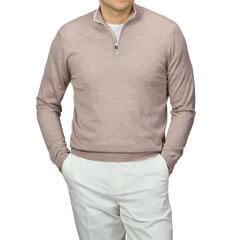 A person in a Fedeli Taupe Beige Cashmere Silk 1/4 Zip Sweater over a white shirt with white pants stands hands-in-pockets against a gray background.