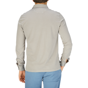 The back view of a man wearing a Fedeli Taupe Beige Organic Cotton LS Polo Shirt and blue pants.