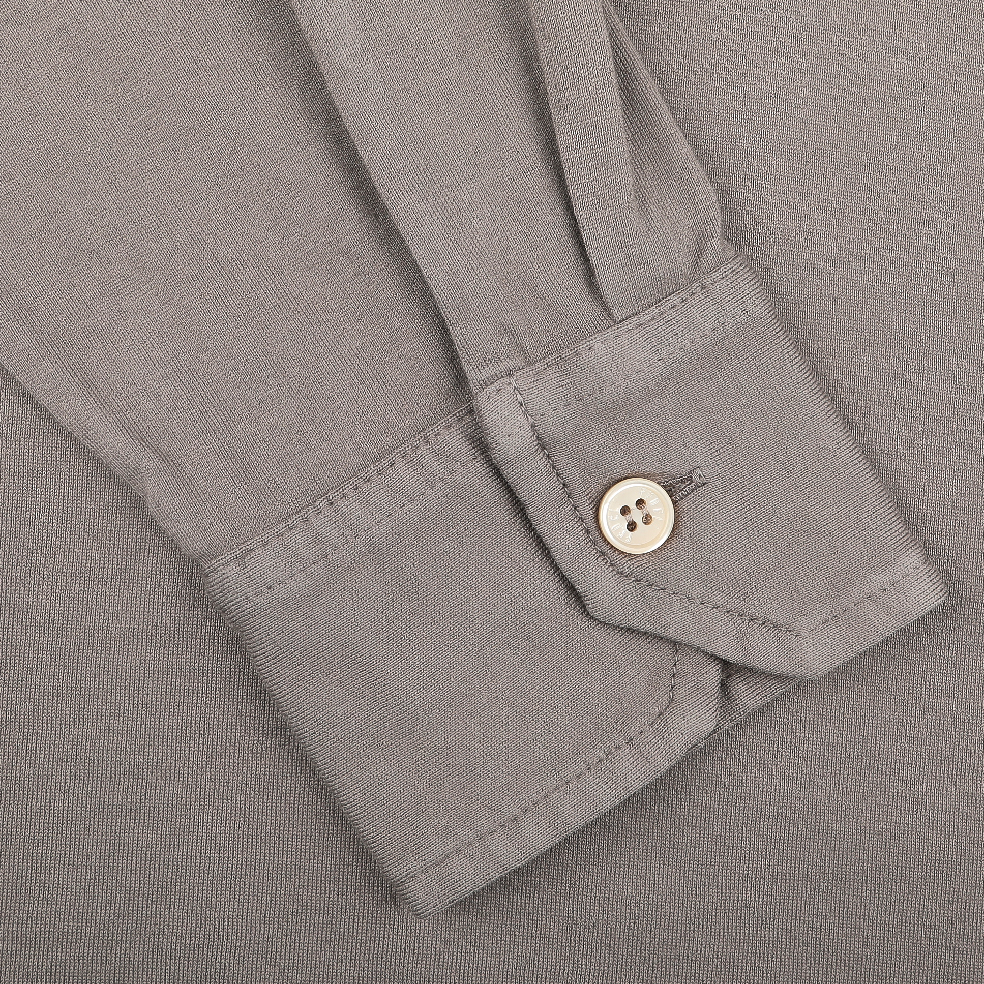 A close-up shows a Taupe Beige LS Polo Shirt from Fedeli, featuring a buttoned cuff on a gray fabric background, crafted from organic cotton.