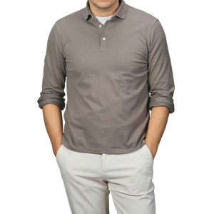 A person in a Fedeli Taupe Beige Organic Cotton LS Polo Shirt and light pants stands with hands in pockets, exuding effortless elegance.