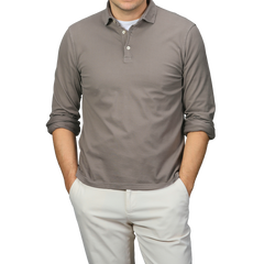 A person in a Fedeli Taupe Beige Organic Cotton LS Polo Shirt and light pants stands with hands in pockets, exuding effortless elegance.