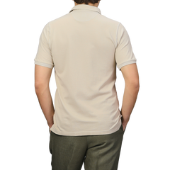 A person is shown from the back wearing a Fedeli Washed Beige Cotton Pique Polo Shirt and olive green pants against a plain gray background.