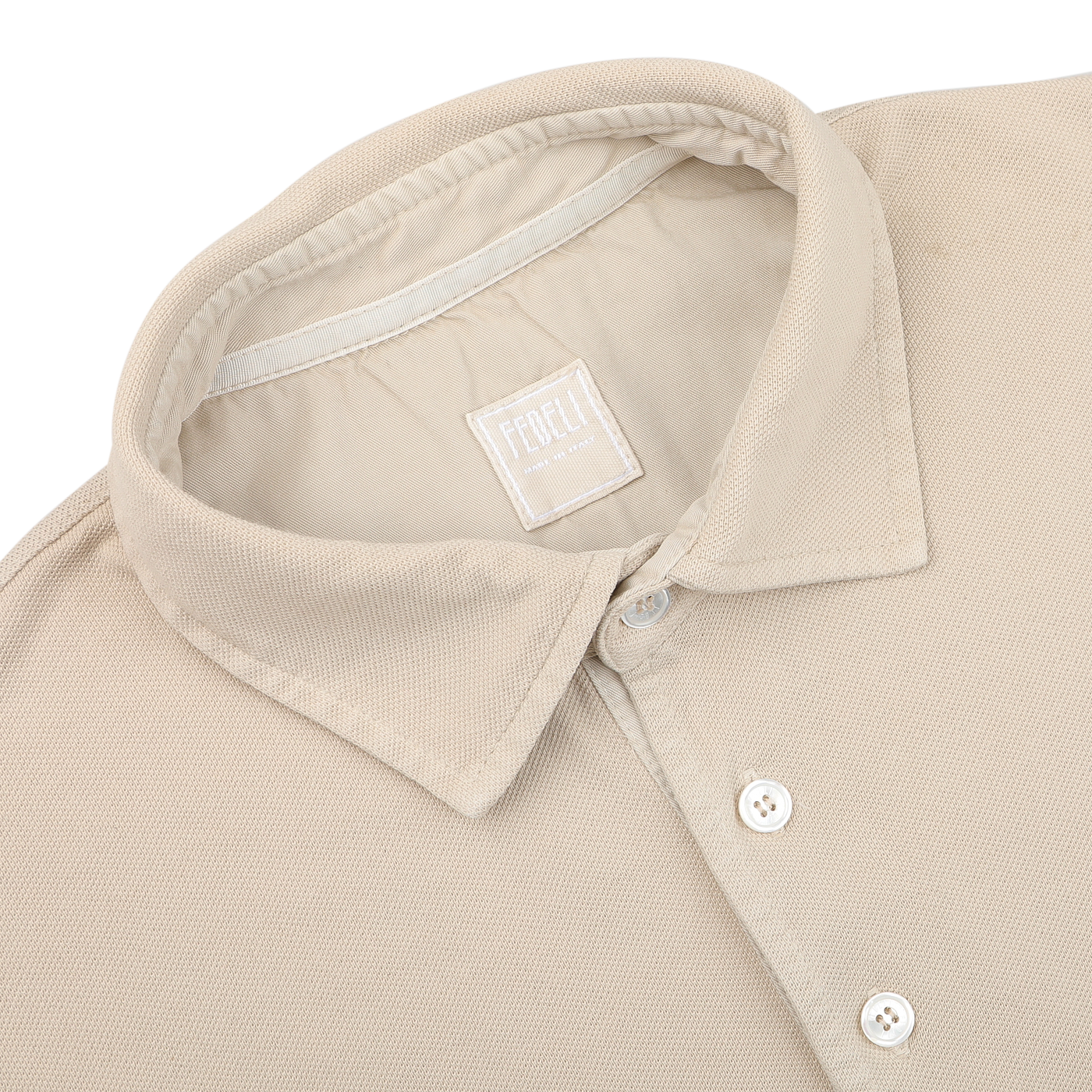 The Washed Beige Cotton Pique Polo Shirt by Fedeli, featuring a collar and white buttons, is folded neatly. Made from superior quality cotton pique, it exudes timeless elegance.