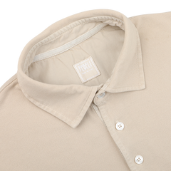 The Washed Beige Cotton Pique Polo Shirt by Fedeli, featuring a collar and white buttons, is folded neatly. Made from superior quality cotton pique, it exudes timeless elegance.