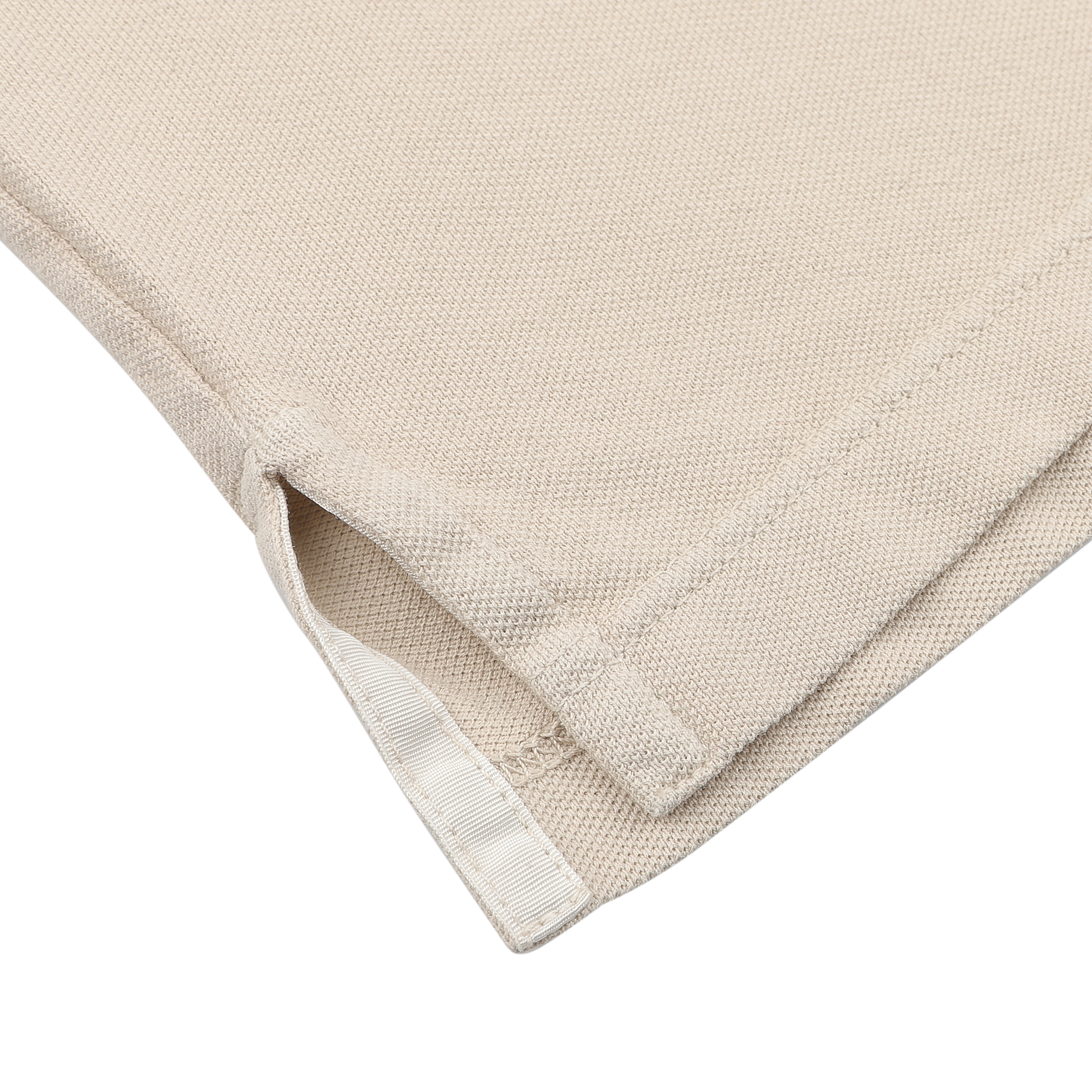 Close-up of a superior quality Washed Beige Cotton Pique Polo Shirt by Fedeli, highlighting a small slit and hem detail against a gray background.