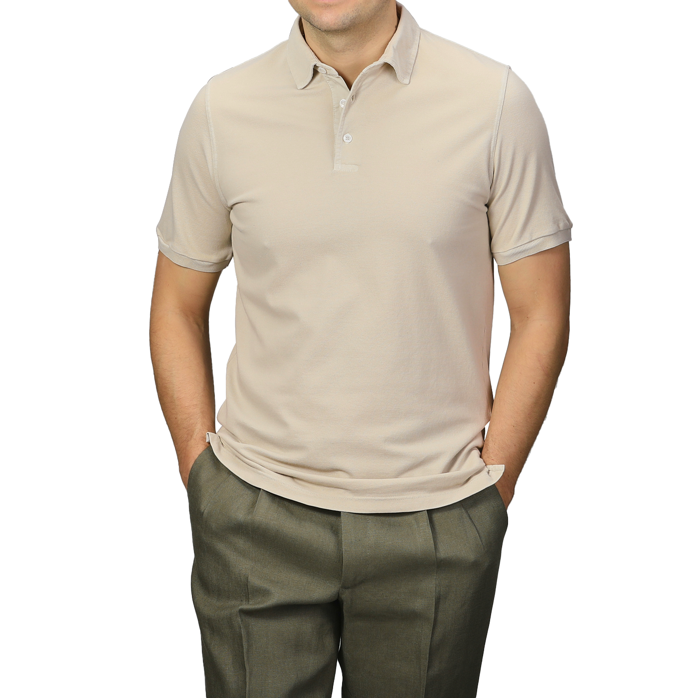 A man wearing a Washed Beige Cotton Pique Polo Shirt by Fedeli and olive pants stands with his hands in his pockets against a gray background.