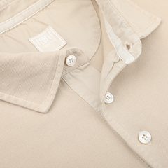 Close-up of a Fedeli Washed Beige Cotton Pique Polo Shirt with buttoned collar, laid flat.