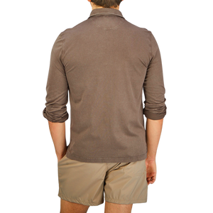 The back view of a man wearing a Fedeli Washed Brown Organic Cotton LS Polo Shirt and shorts, casually blending luxury into his outfit.