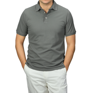 A person stands confidently against a neutral background, wearing a premium Washed Green Cotton Pique Polo Shirt by Fedeli and white pants, hands casually tucked in pockets.