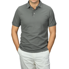 A person stands confidently against a neutral background, wearing a premium Washed Green Cotton Pique Polo Shirt by Fedeli and white pants, hands casually tucked in pockets.