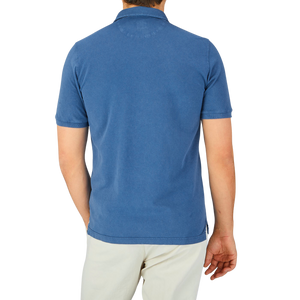 The back view of a man wearing a Fedeli Washed Light Blue Cotton Pique Polo Shirt in superior quality.