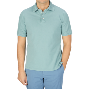 A man wearing a Fedeli washed light green cotton pique polo shirt and blue pants.