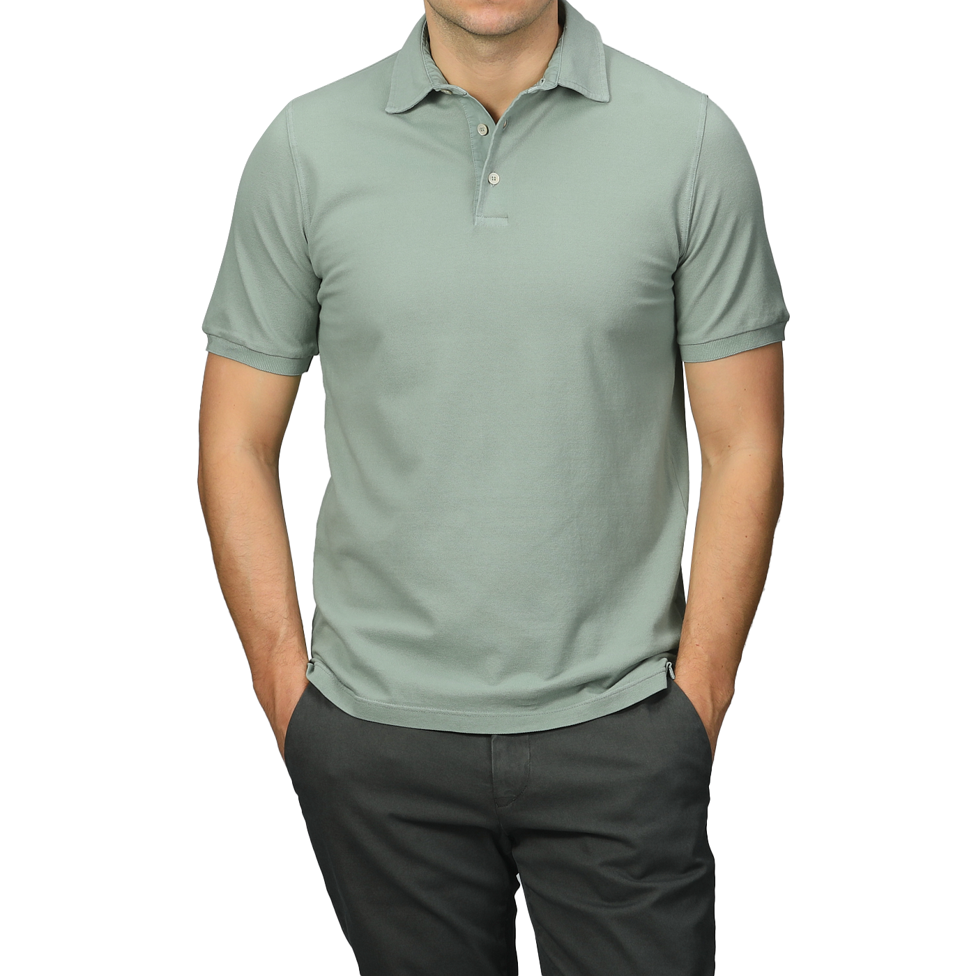 A person dressed in a Washed Light Green Cotton Pique Polo Shirt by Fedeli and dark pants, hands in pockets, ideal for a summer wardrobe.