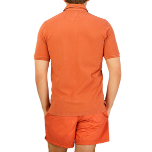 The back view of a man wearing a Fedeli Washed Rust Cotton Pique Polo Shirt.
