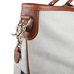 Close-up of the Felisi Navy Grey Cotton Canvas Leather Travel Tote, showcasing vacchetta calf leather trim and a gold-toned metal clip attached to the strap.