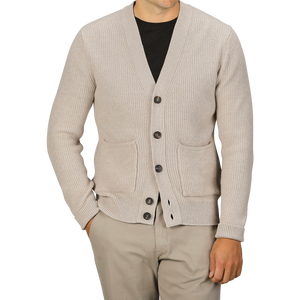 A person wearing a Filippo de Laurentiis Beige Melange Wool Cashmere Cardigan with ribbed hems and black buttons over a black shirt and beige pants against a plain background. The luxurious cardigan, featuring two front pockets, is made from a blend of wool and cashmere.