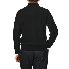 A person in a sleek black cashmere rib knit cardigan by Filippo de Laurentiis and dark pants, viewed from the back, showcases a regular fit.