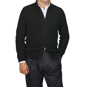 A person wearing a Filippo de Laurentiis Black Cashmere Rib Knit Cardigan over a white shirt and gray pants.