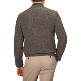 A person stands with their back facing the camera, wearing a Filippo de Laurentiis Brown Melange Yak Cashmere Sweater and beige pants.