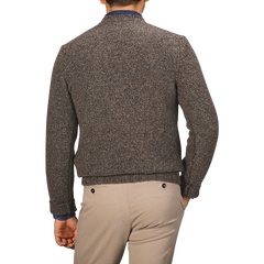 A person stands with their back facing the camera, wearing a Filippo de Laurentiis Brown Melange Yak Cashmere Sweater and beige pants.