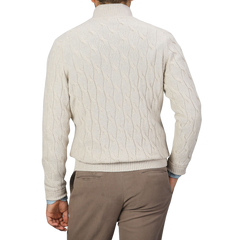 A person stands facing away from the camera, wearing a Filippo de Laurentiis Cream Wool Cashmere Cableknit Button Cardigan, paired with brown pants.