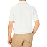 The back view of a man wearing a Filippo de Laurentiis Latte White Crepe Cotton Polo Shirt and tan pants.