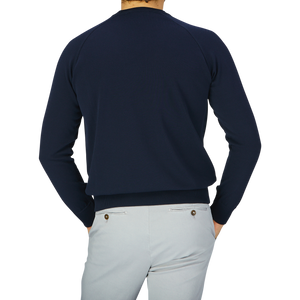 The back view of a man wearing a Filippo de Laurentiis Navy Blue Crepe Cotton Crew Neck Sweater and grey pants.