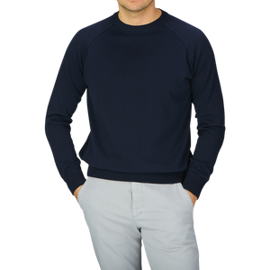A man wearing a Filippo de Laurentiis navy blue crepe cotton crew neck sweater and grey pants.