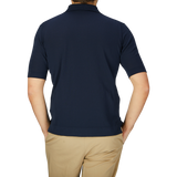 A man viewed from the back wearing a slim fit Filippo de Laurentiis navy blue crepe cotton polo shirt and khaki pants against a light gray background.
