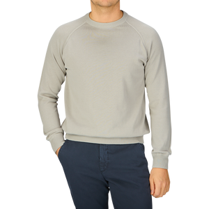A man wearing a Filippo de Laurentiis Nebbia Grey Crepe Cotton Crew Neck Sweater and blue pants.