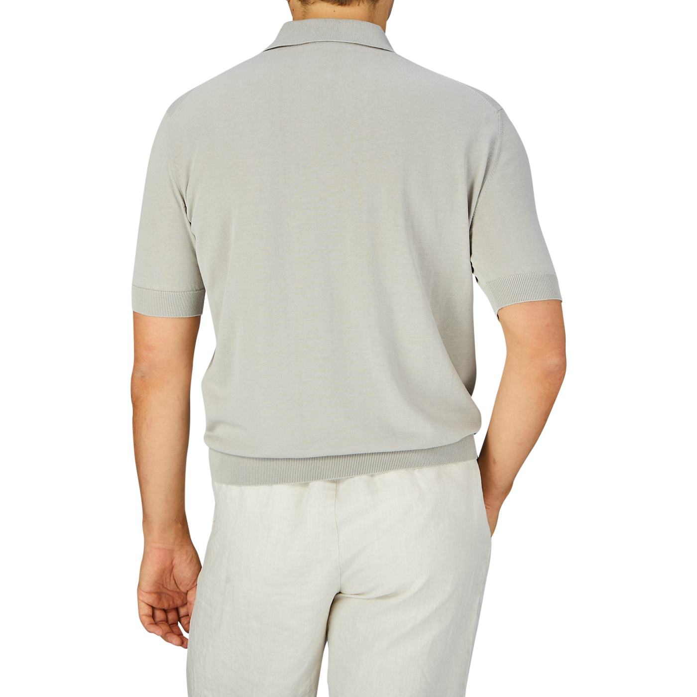 Man standing with his back to the camera wearing a slim fit Nebbia Grey Crepe Cotton Polo Shirt by Filippo de Laurentiis and white pants.