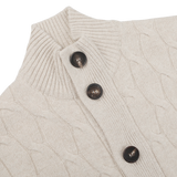 Close-up of the Filippo de Laurentiis Cream Wool Cashmere Cableknit Button Cardigan, showcasing a delicate beige pattern and three dark brown buttons.