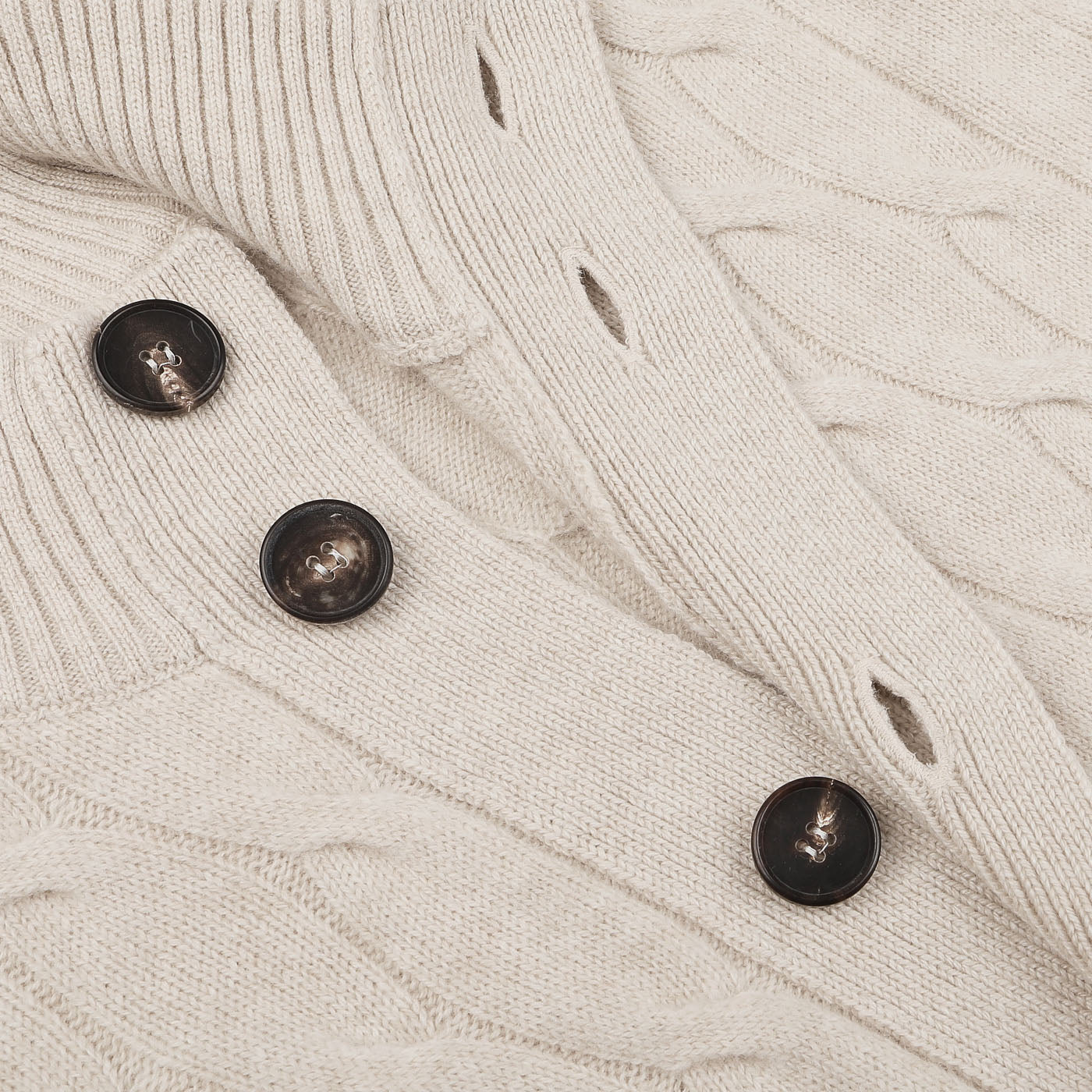 Close-up of a Filippo de Laurentiis Cream Wool Cashmere Cableknit Button Cardigan with three large brown buttons. This splendid piece, made from a luxurious blend of wool and cashmere, features a braided pattern with ribbing near the button closure.