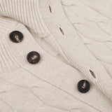 Close-up of a Filippo de Laurentiis Cream Wool Cashmere Cableknit Button Cardigan with three large brown buttons. This splendid piece, made from a luxurious blend of wool and cashmere, features a braided pattern with ribbing near the button closure.