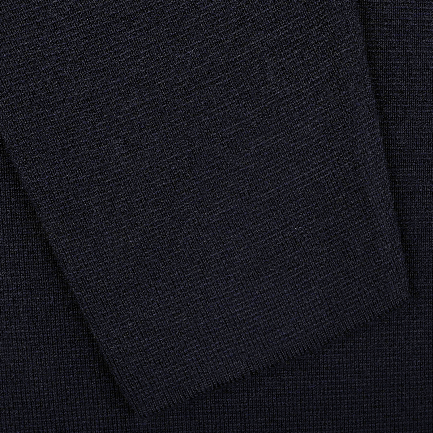 Close-up of a navy blue, textured extrafine merino wool fabric, crafted in Italy by Filippo De Laurentiis, with a piece elegantly folded over the main section.