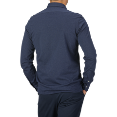 A person is shown from the back, wearing a long-sleeved Blue Melange Cotton Cashmere Jersey Polo Shirt from Finamore and dark blue pants. The background is plain gray.