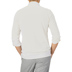 A person is seen from the back wearing an Ecru Cotton Cashmere Jersey Polo Shirt by Finamore and grey pants, with their hands resting on their hips.