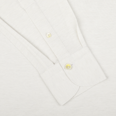 Close-up of the Finamore Ecru Cotton Cashmere Jersey Polo Shirt, showcasing the cuff with two buttons and part of the sleeve. The slim fit design highlights the luxurious cotton-cashmere blend fabric.