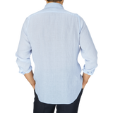 Man standing with his back to the camera, wearing a Finamore light blue linen casual shirt and dark trousers.