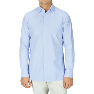 A man in a Finamore Light Blue Washed Cotton Twill Shirt and white pants.