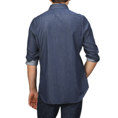 A person with rolled-up sleeves is shown from the back, effortlessly sporting a Medium Blue Cotton Denim Casual Shirt by Finamore and jeans.