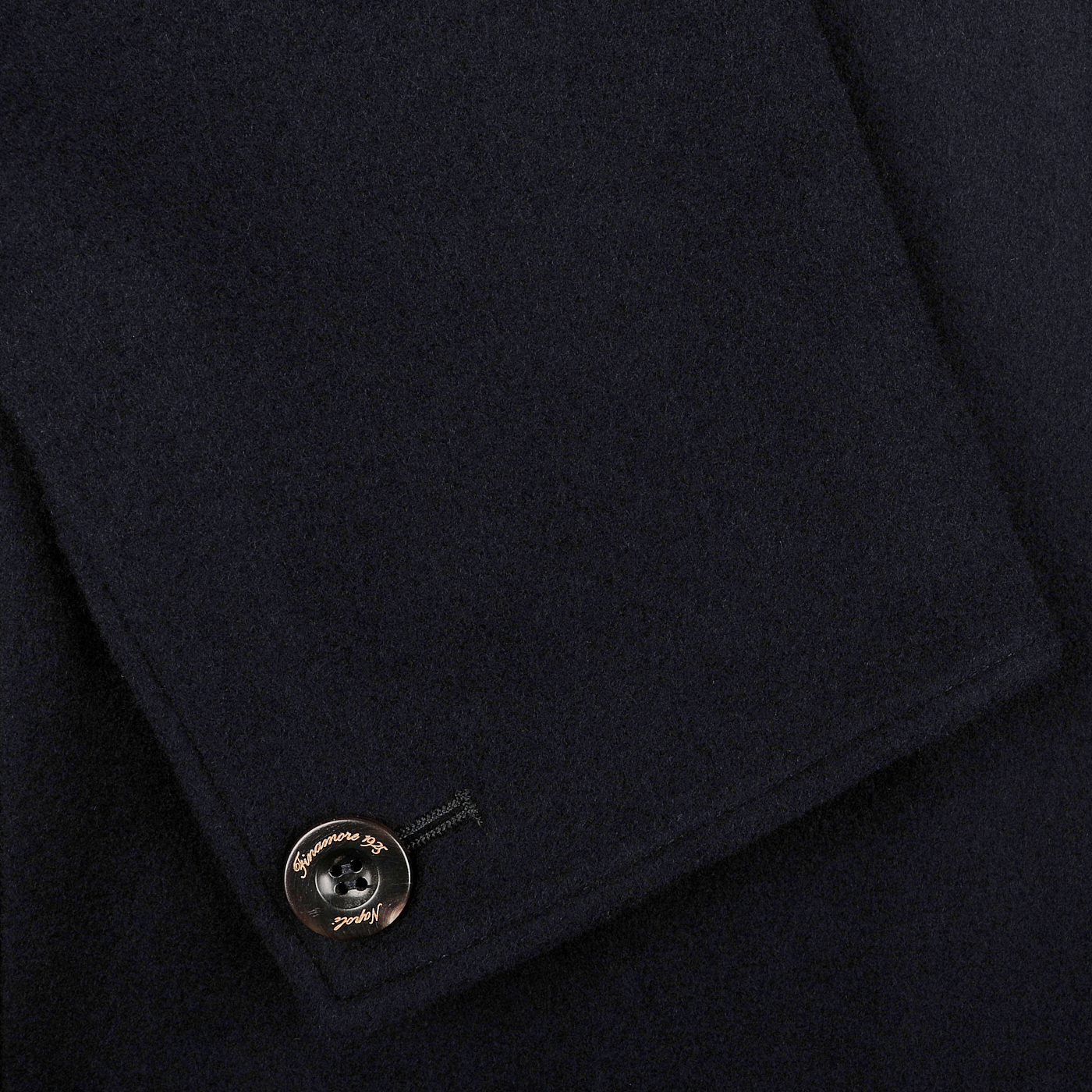 Close-up of the Navy Blue Boiled Wool Casual Blazer by Finamore, showcasing its dark boiled wool fabric with a folded edge and adorned with a metallic button featuring an engraved logo, ideal for that casual blazer look.